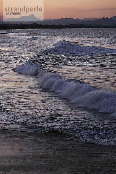 Wellen schlagen bei Sonnenuntergang auf den Strand von Byron Bay in New South Wales  Australien