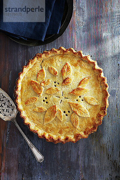 Tourtiere mit verzierter Kruste auf blauem Holzgrund