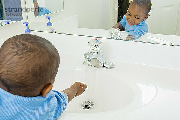 Kleinkind wäscht seine Hände im Badezimmerwaschbecken