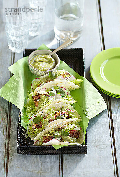 Serviertablett mit Fisch-Tacos mit Guacamole und Beilagen