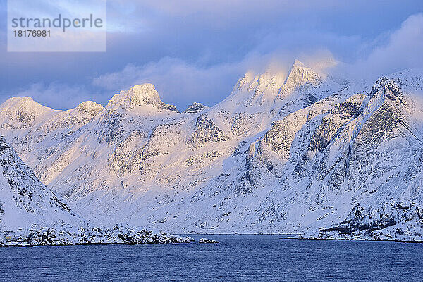 Blick von der Spellmannsbukta auf die Insel Kunna und Flakstadoya. Berge im Winter mit Schnee bedeckt  Sonnenuntergang. Kunna Island  Flakstadoy  Lofoten  Norwegen  Skandinavien.