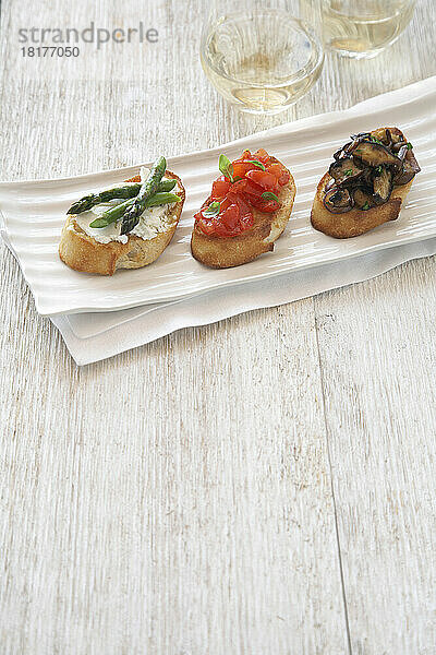 Crostini garniert mit Spargel  Tomaten und Pilzen  serviert auf einer Platte