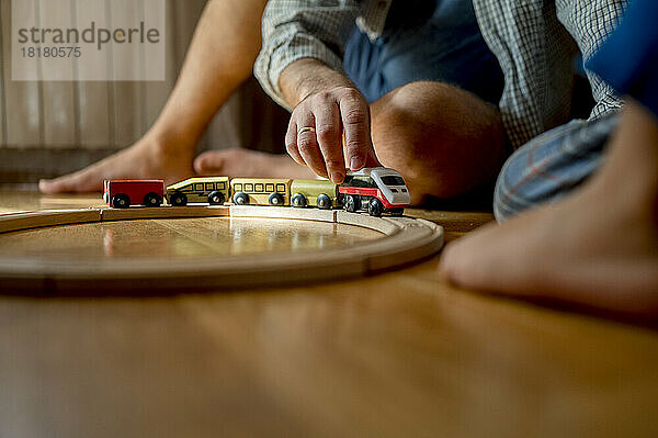 Father playing with toy train on floor at home