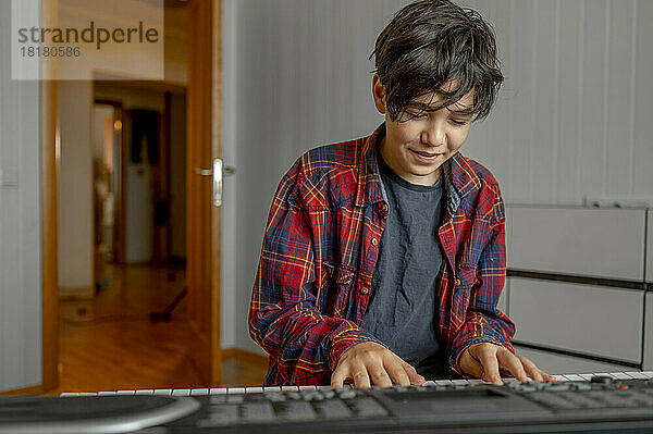 Lächelnder Junge  der zu Hause Synthesizer lernt