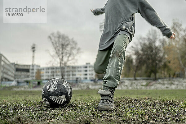 Junge kickt Fußball auf Sportplatz