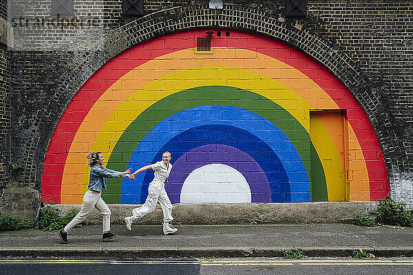 Sorgloses lesbisches Paar hält Händchen und rennt auf Fußweg