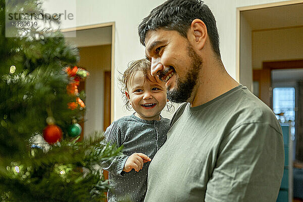 Lächelnder Vater und Sohn schauen auf den Weihnachtsbaum