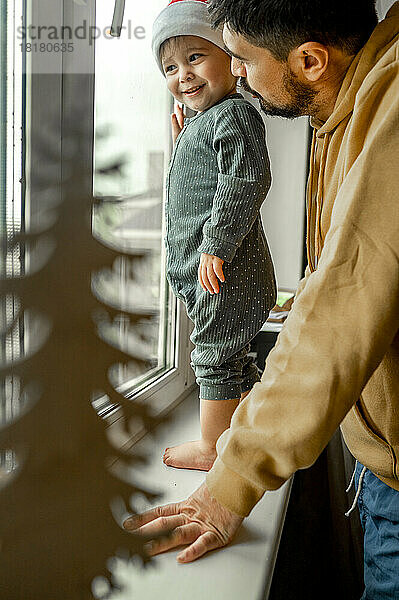 Sohn und Vater stehen zu Hause am Fenster