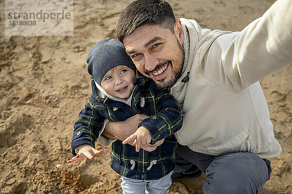 Glücklicher Vater macht Selfie mit Sohn am Strand
