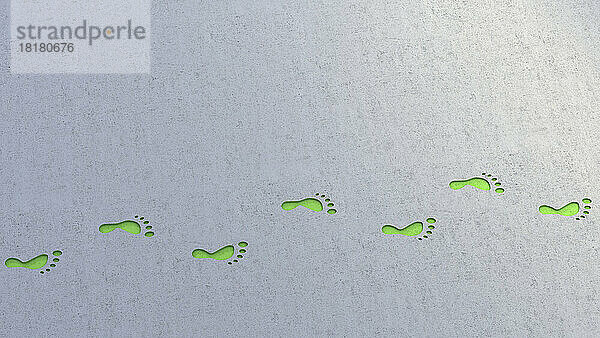 Illustration grüner Fußabdrücke  die sich über einen grauen Hintergrund erstrecken