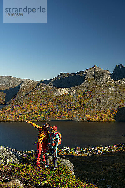Couple standing at mountain and pointing on sunny day