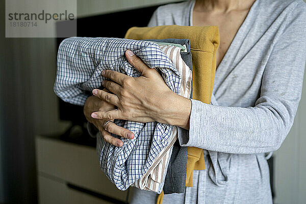 Frau hält gebügelte  gefaltete Kleidung zu Hause