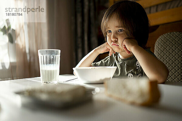 Verärgerter Junge mit Essen auf dem Esstisch zu Hause