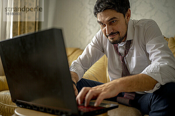 Entschlossener Geschäftsmann  der zu Hause am Laptop arbeitet