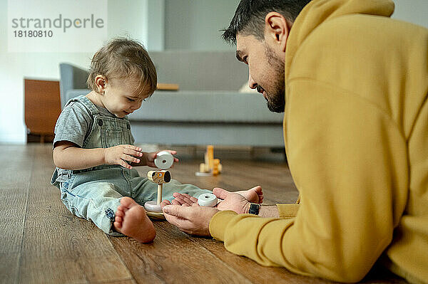 Vater und Sohn spielen mit Holzspielzeug im Wohnzimmer