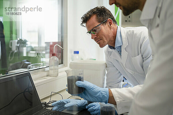 Wissenschaftler und Kollege nutzen Laptop und arbeiten im Labor an einem Thermolyse-Experiment