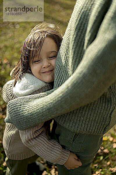 Lächelnder Junge umarmt Bruder im Park
