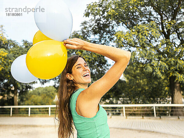 Fröhliche Frau  die Spaß mit Luftballons am Fußweg hat