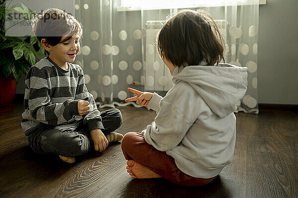 Brüder spielen zu Hause Stein-Papier-Schere auf dem Boden
