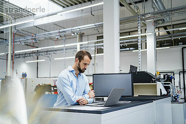 Geschäftsmann mit Laptop auf Tisch in der Industrie