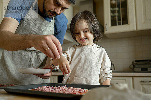 Vater und Sohn backen in der heimischen Küche Pizza