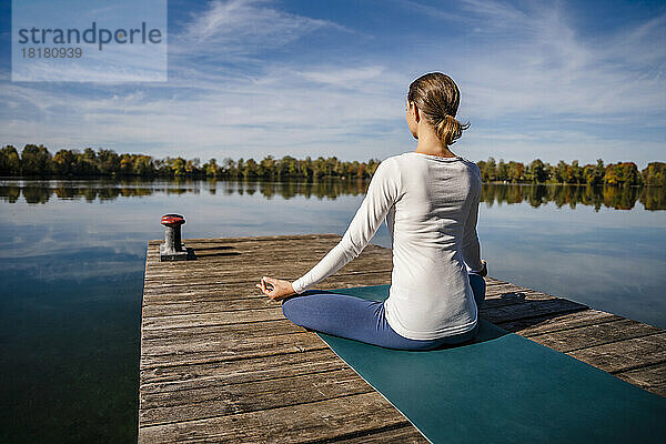 Frau praktiziert Meditation vor dem See