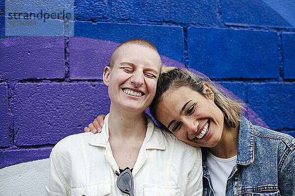 Fröhliches lesbisches Paar  das Spaß vor der Wand hat