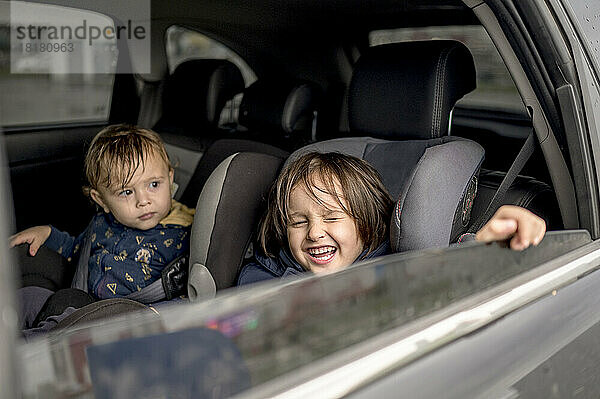 Glückliche Geschwister sitzen auf dem Rücksitz des Autos