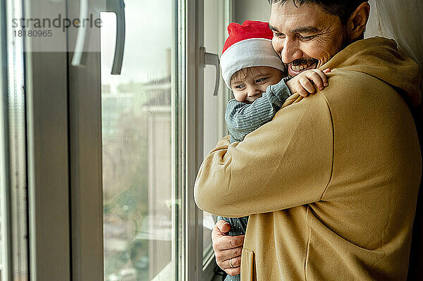 Vater umarmt Sohn am Fenster zu Hause