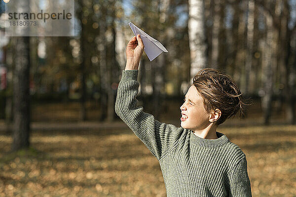 Junge spielt mit Papierflieger im Park