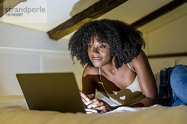 Afro-Frau schaut sich zu Hause im Schlafzimmer einen Film auf dem Laptop an