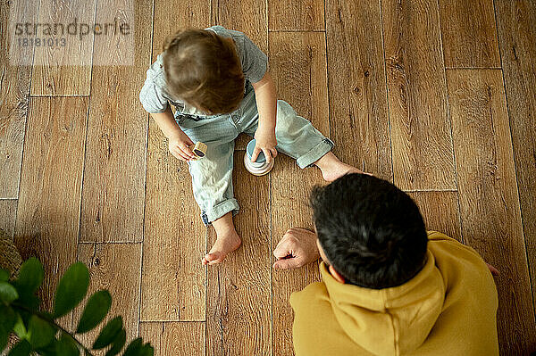 Father playing with boy on hardwood floor at home