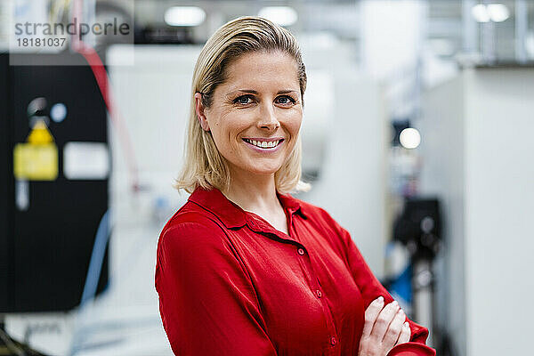 Glückliche Geschäftsfrau im roten Hemd in der Fabrik