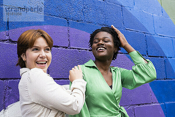 Glückliches lesbisches Paar genießt es vor einer bunten Wand