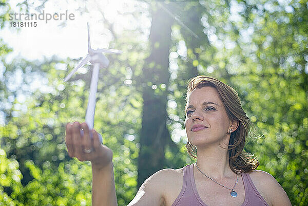 Frau hält an sonnigem Tag Windturbinenmodell im Park