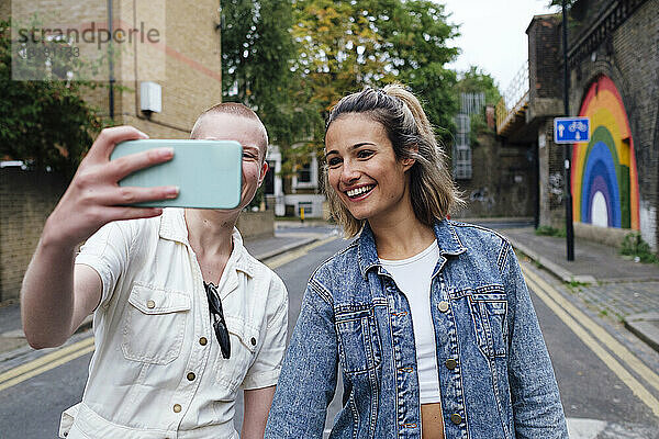 Nicht-binäre Person  die auf der Straße ein Selfie mit dem Smartphone macht