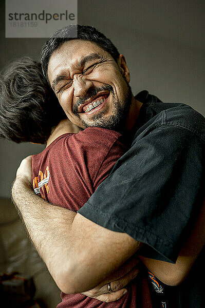 Fröhlicher Vater umarmt Sohn zu Hause