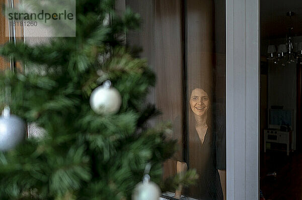 Glückliche Frau blickt auf den Weihnachtsbaum