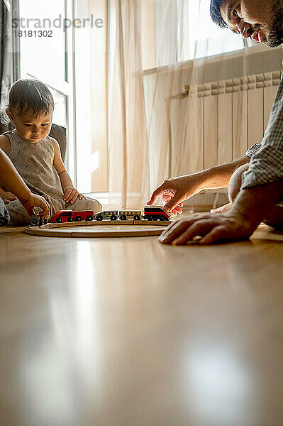 Father spending leisure time with sons playing toy at home