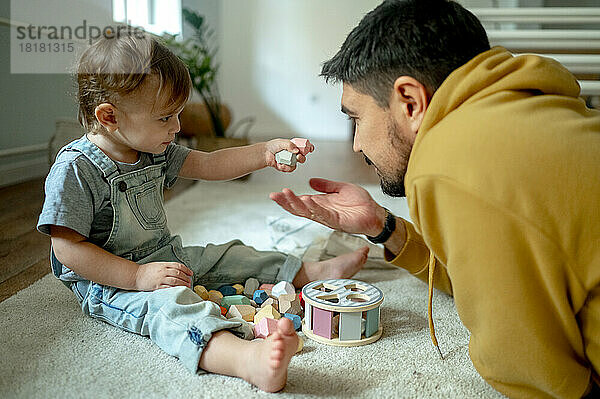 Vater und Sohn spielen zu Hause mit Holzspielzeug auf dem Teppich