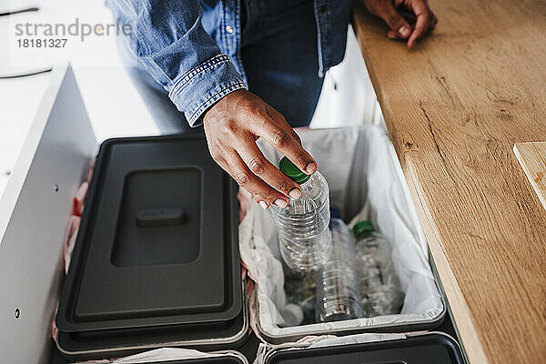 Hände einer Frau  die zu Hause Plastikflaschen in der Küche recycelt