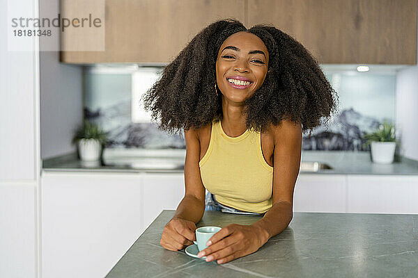 Glückliche Afro-Frau mit Kaffeetasse in der Küche