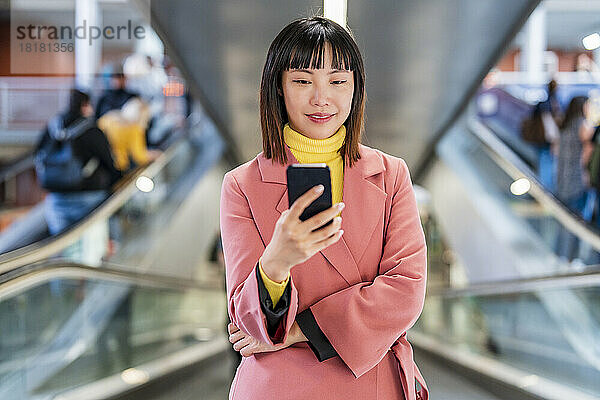 Lächelnde junge Frau  die auf Rolltreppe im Internet surft