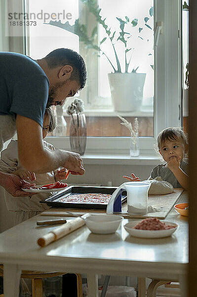 Glücklicher Vater und Sohn bereiten zu Hause gemeinsam Pizza zu