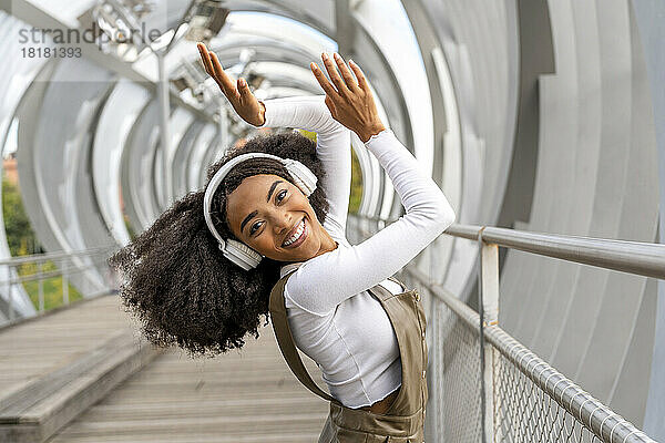 Glückliche Frau genießt es  über Kopfhörer auf der Fußgängerbrücke Musik zu hören