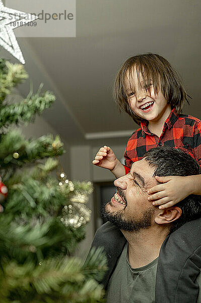 Sohn und Vater amüsieren sich zu Hause am Weihnachtsbaum