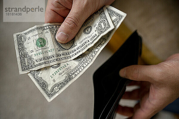 Hände eines Mannes  der Geld aus der Brieftasche nimmt