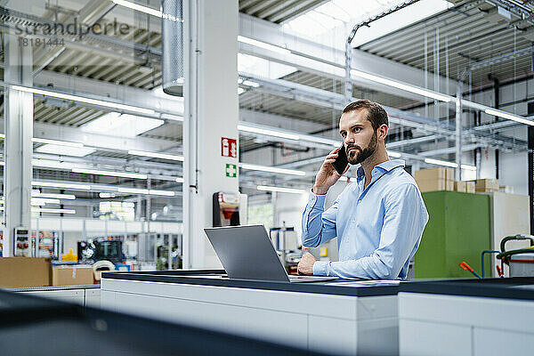 Geschäftsmann  der in der Industrie mit dem Mobiltelefon spricht