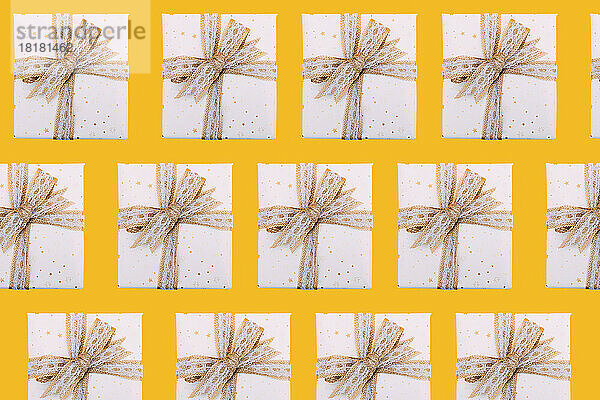 Multiple image of gift boxes wrapped in white paper against yellow background