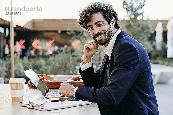 Hübscher Geschäftsmann mit Laptop am Tisch  der im Café arbeitet